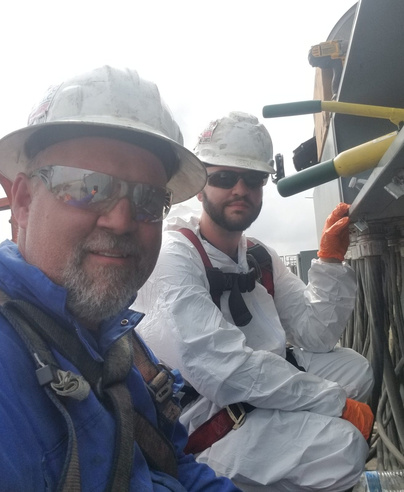 Ed Wheat and Jamie in hard hats and work clothes on plant equipment