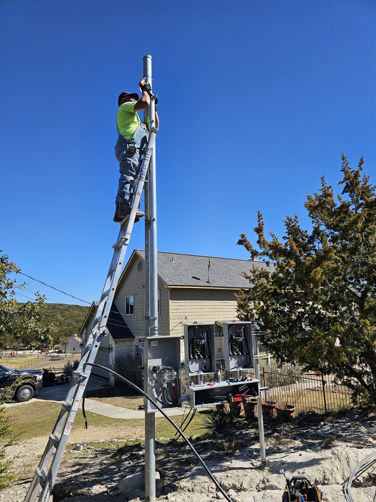 Electrician on an extension ladder working the top of a service pole