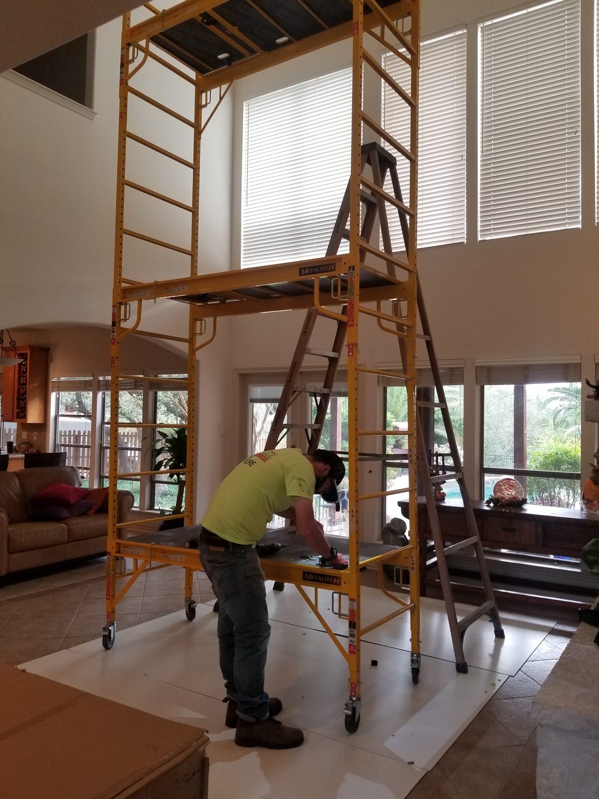 Yellow scaffold on floor protection paper in a high-ceiling living room