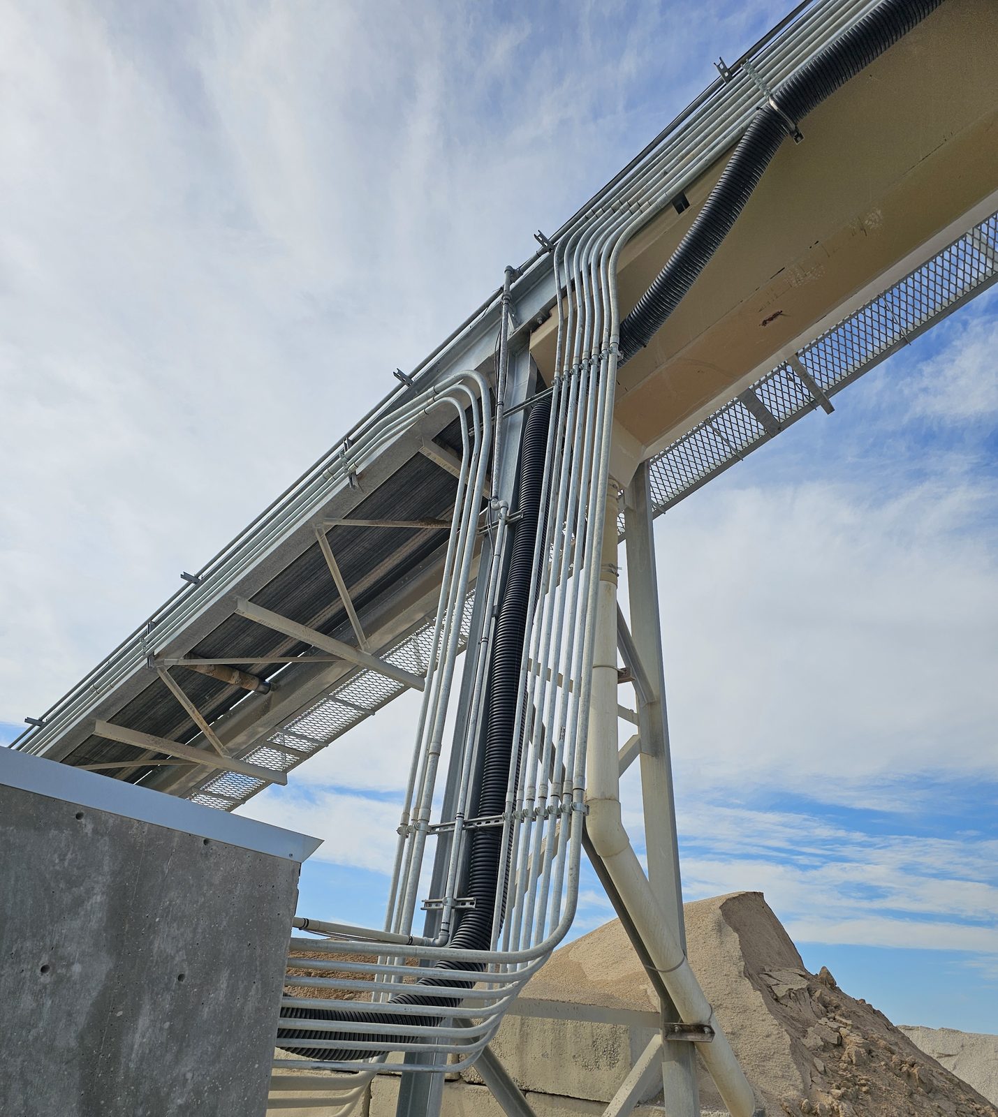 Galvanized conduit running along an outdoor conveyor