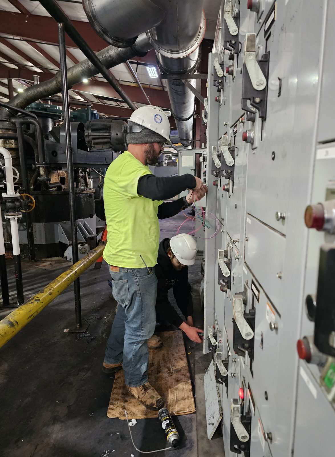 Two Wheat Electric crew members working a motor control center